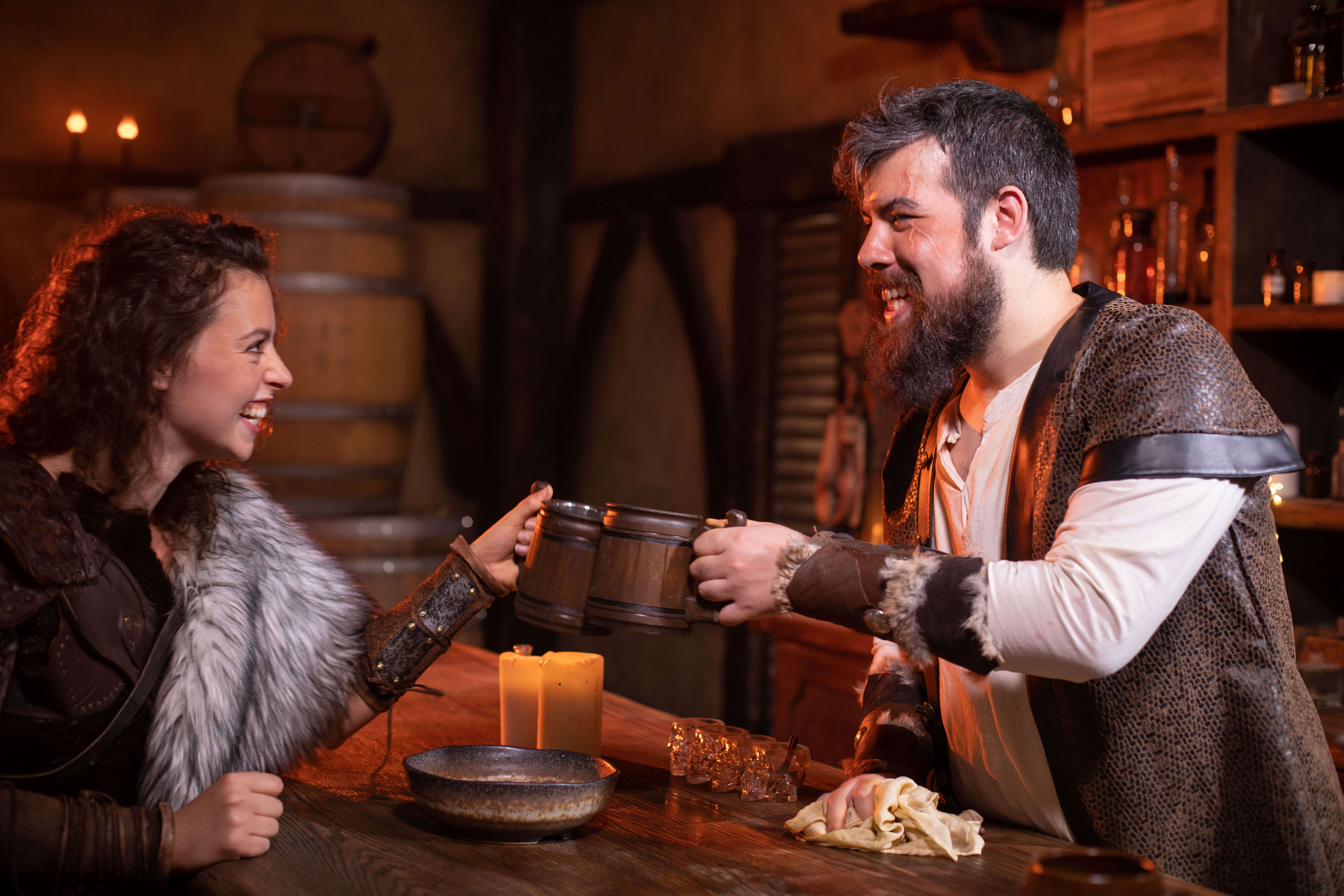 Two people in a dungeons and dragons tavern clink glasses joyfully